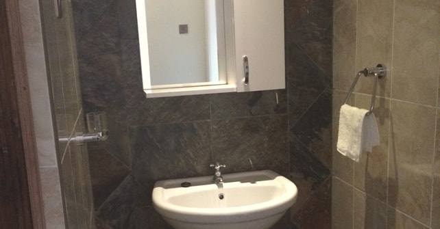 Deluxe Room shower room with stone-effect tiles and a wall basin